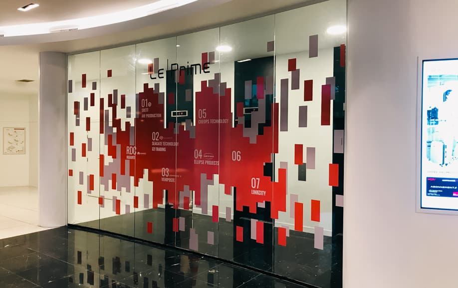 Film vitrage décoratif design rouge et gris sur la façade vitrée de l’accueil d’un immeuble de bureaux