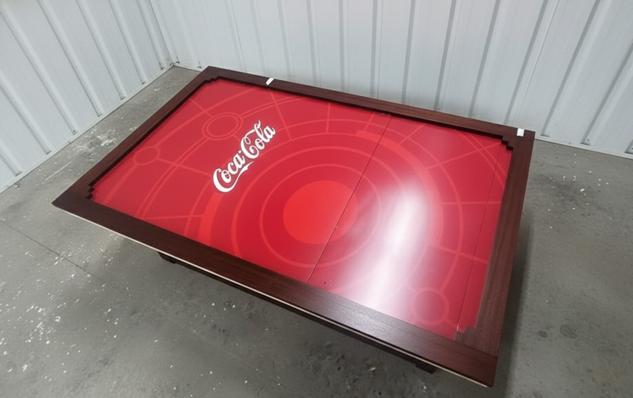 Détail d’un logo adhésif Coca-Cola sur meuble verni