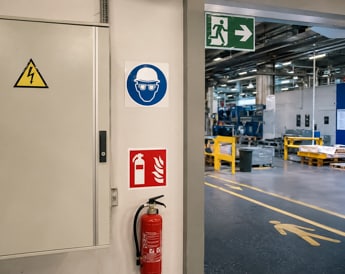 Panneaux de signalétique de sécurité conformes dans un couloir d'entreprise