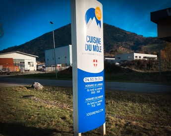 Totem publicitaire extérieur devant l'entrée d'une entreprise, avec logo et informations